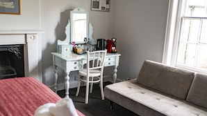 A bedroom with a bed, a dresser, a chair, a sofa, a fireplace, and a window.