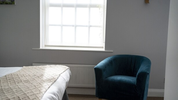 Une chambre à coucher avec un lit, une fenêtre et un fauteuil bleu.