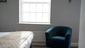 Un dormitorio con cama, ventana y un sillón azul.
