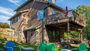 Una casa de dos pisos con un porche cubierto, mobiliario exterior y una chimenea.