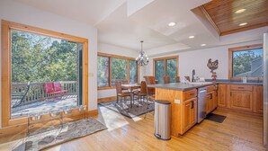 Una cocina amplia con armarios de madera, una isla central y grandes ventanales con vistas al exterior.
