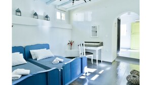 A bedroom with a blue bed, white walls, and a window. - Amazing 1-Bedroom House in Tinos (Tinos)