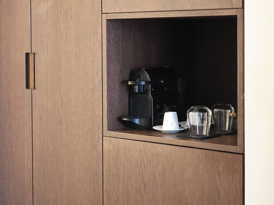 Un meuble en bois doté d’une machine à café intégrée et de verres.