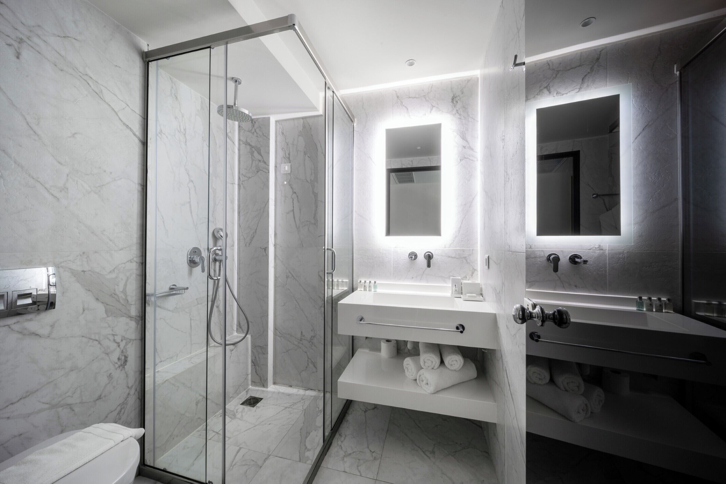A modern bathroom with a glass-enclosed shower, a vanity with a mirror, and a toilet.