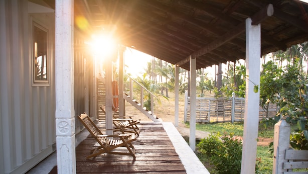 A wooden porch with white railings and a wooden bench. - Rüstic Beach Villa (Mundalama)