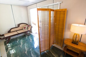 A room with a wooden floor, a sofa, a lamp, and a sliding door. - Rüstic Beach Villa (Mundalama)