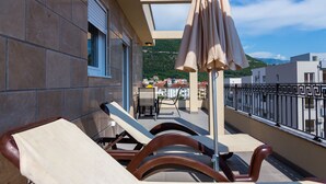 Ein Balkon mit zwei Loungestühlen und einem Tisch, der einen schönen Ausblick auf Gebäude und Hügel bietet.