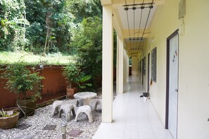 A corridor with a tiled floor, potted plants, and a small table with chairs.
