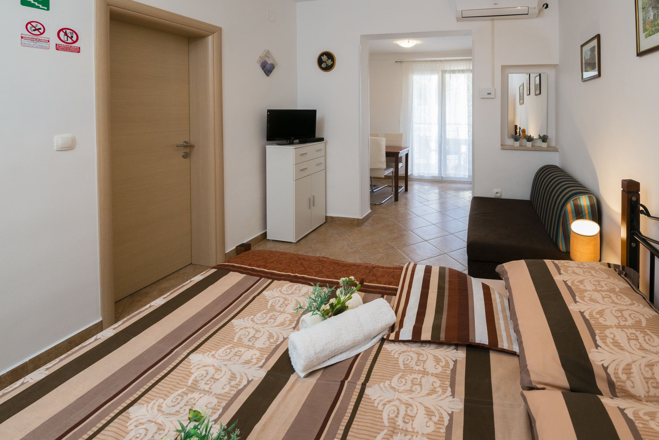 A hotel room with a bed, a TV, a desk, and a dining area.