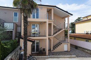 A two-story building with a balcony, a staircase, and a patio area.