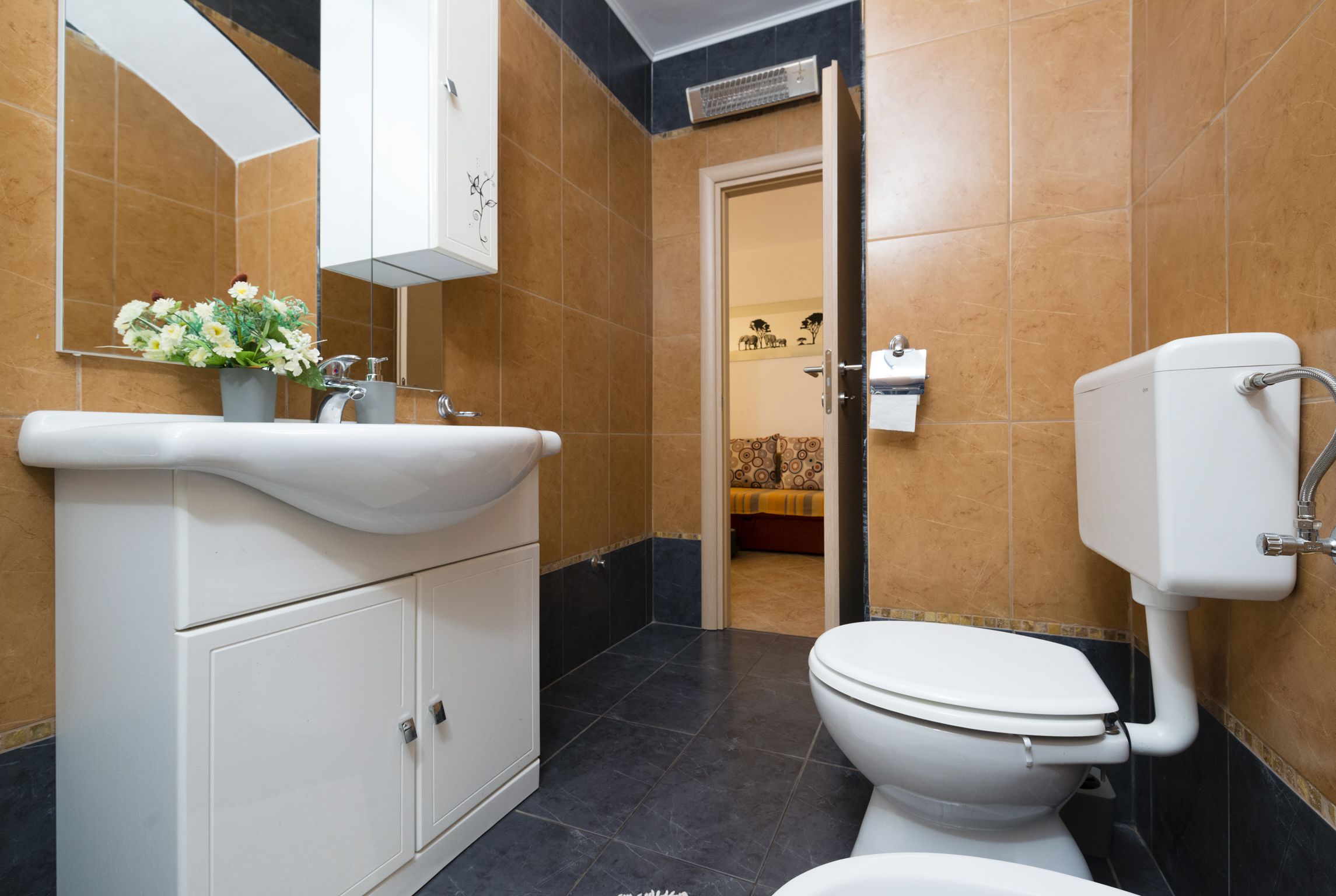 A modern bathroom with a white sink, a toilet, and a mirror.