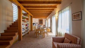 A spacious living area with a wooden staircase, a dining table with chairs, and a sofa. - La Casa nel Borgo: Lake View Terrace, Nebbiuno, Italy (Nebbiuno)