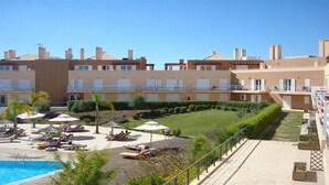 Un hotel con piscina, tumbonas y un jardín bien cuidado.