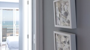 Una habitación con una cama, vista al océano y tres cuadros en la pared.
