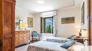 Une chambre avec deux lits, une commode, une chaise et une fenêtre donnant sur un beau paysage.