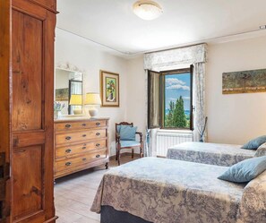 Een slaapkamer met twee bedden, een dressoir, een stoel en een raam met uitzicht.