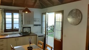 Una cocina con ventana, un reloj y una mesa con un florero.