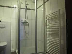 A bathroom with a glass-enclosed shower, a white toilet, and a towel rack. - House Deichläufer Apartment Möwenblick No. 1 (Warwerort)