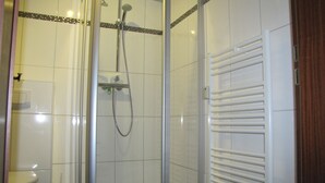A shower with a glass door, a toilet, and a towel rack.