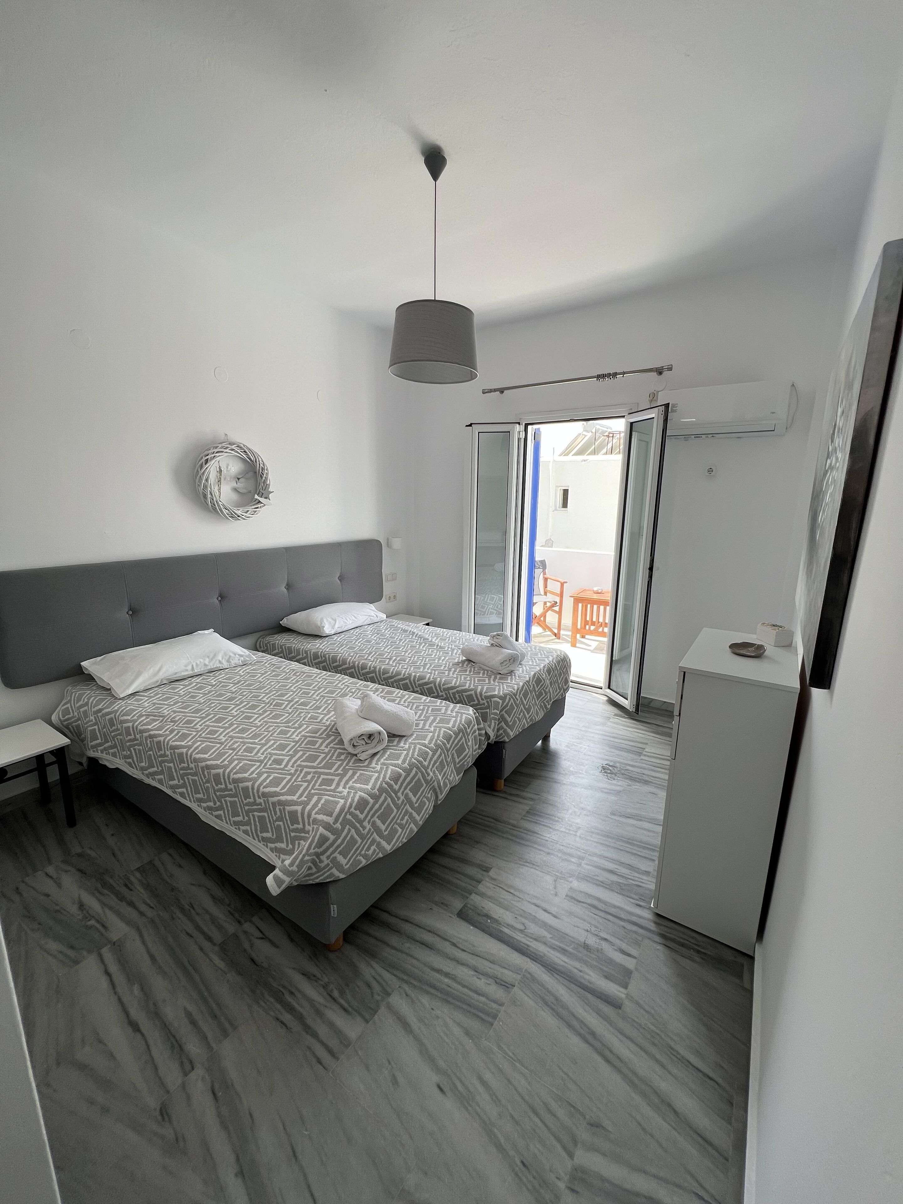 Quarto moderno com duas camas, uma escrivaninha pequena e um guarda-roupa.