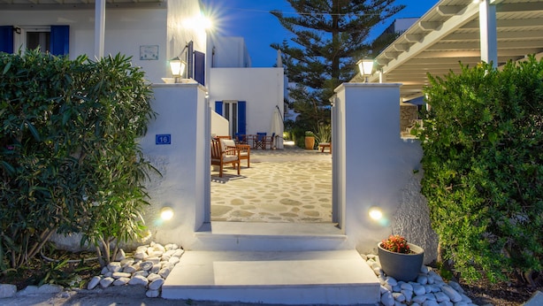 A courtyard with a stone floor, outdoor furniture, and a large tree. - Marioly Studios (Paros)