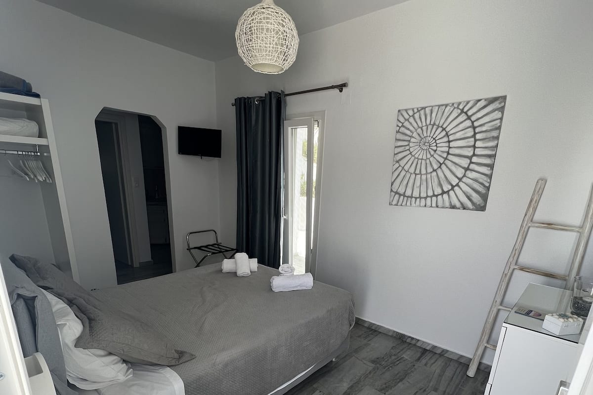 A modern bedroom with a bed, bedside table, wardrobe, and a hanging light fixture.
