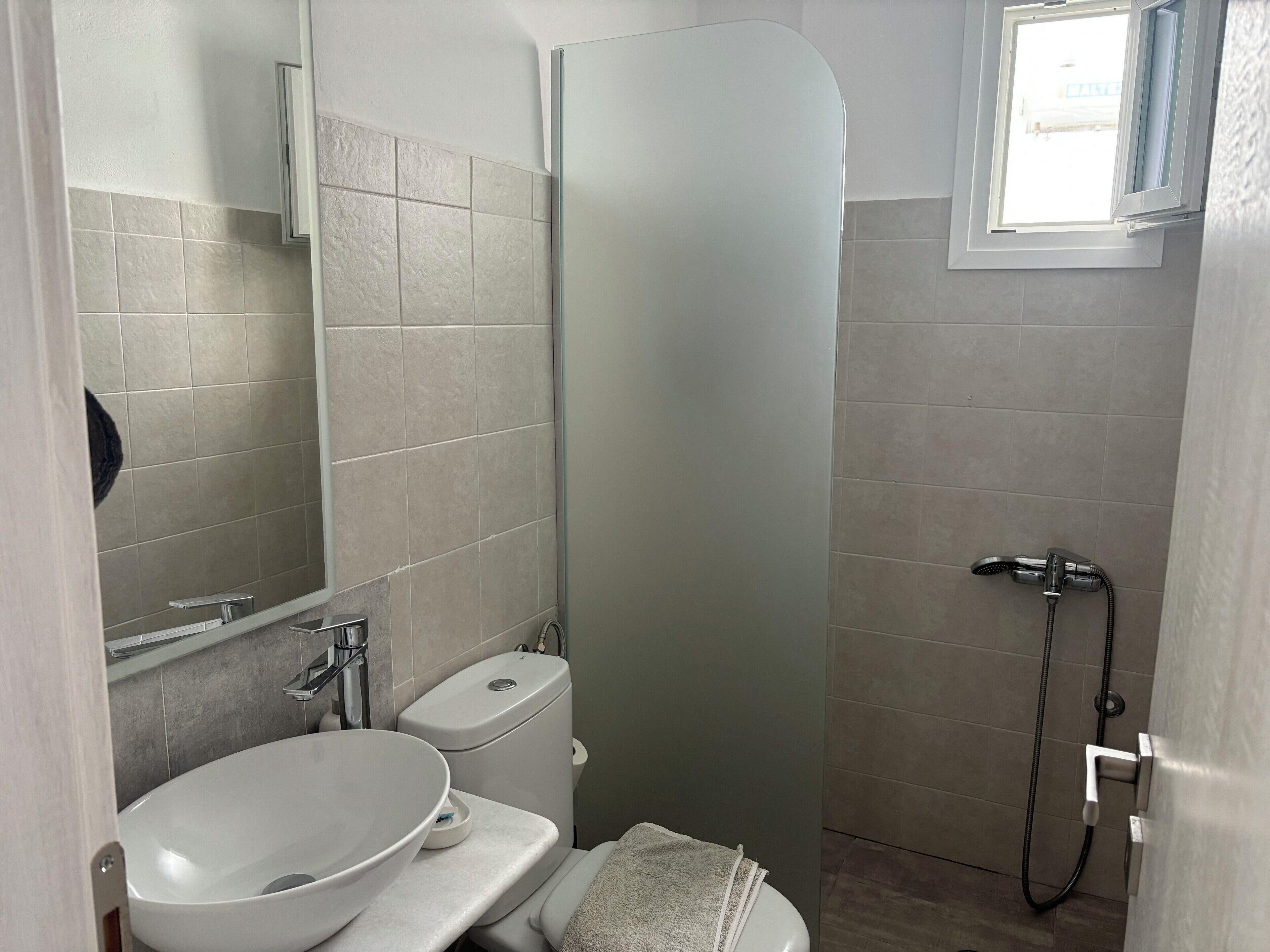 Un baño con lavamanos, inodoro y ducha blancos.