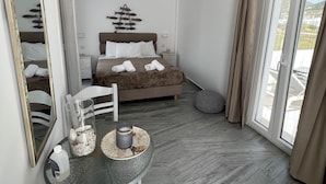 A modern bedroom with a bed, a dining table, and a large window. - Marioly Studios (Paros)