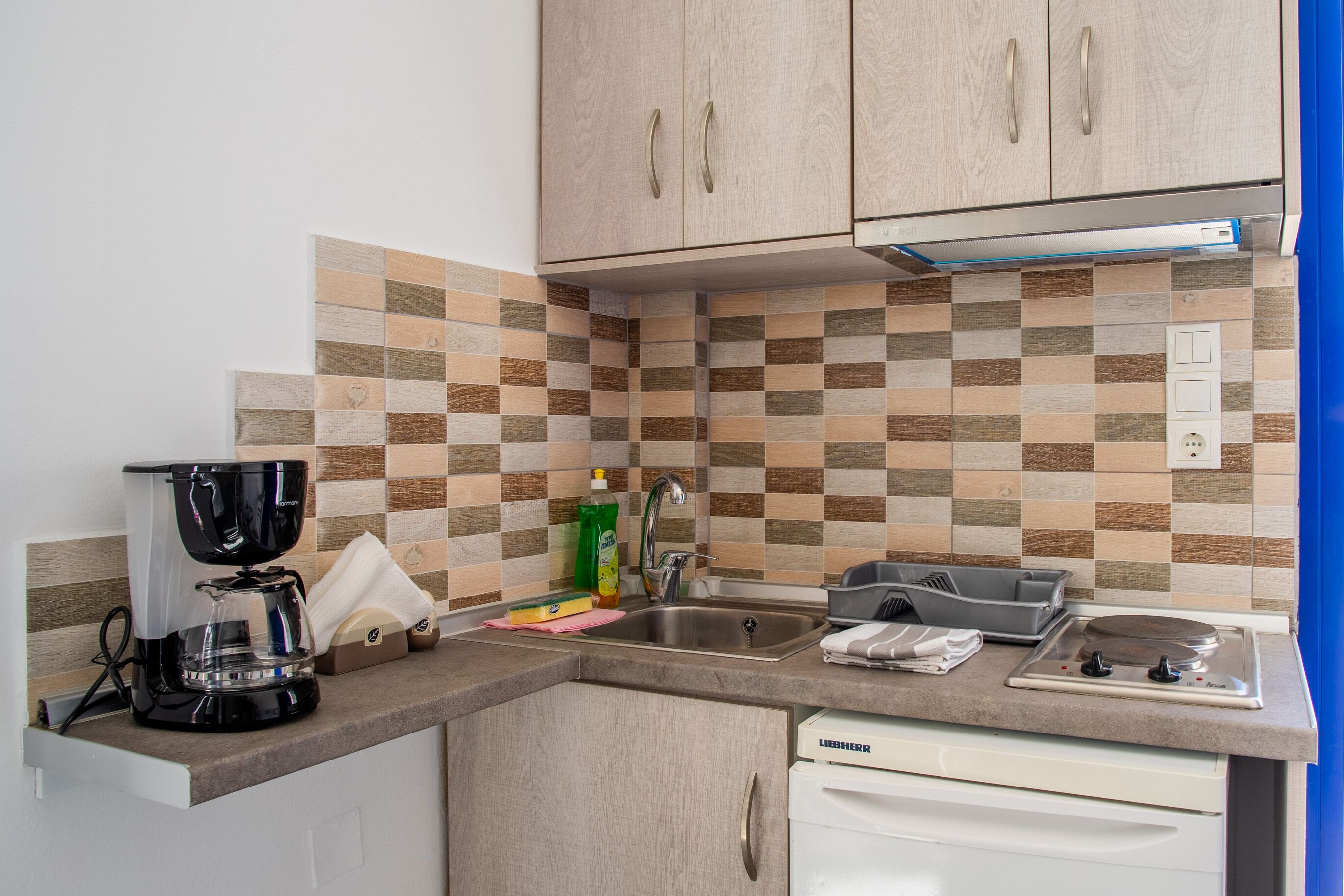 A kitchen with a coffee maker, sink, and a dish rack.