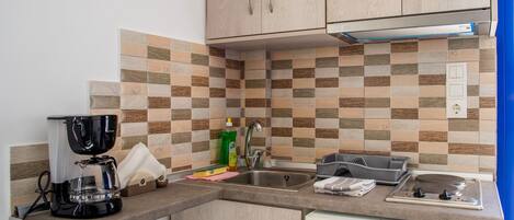 A kitchen with a coffee maker, sink, and a dish rack.