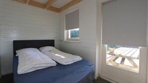 Un dormitorio con cama, ventana con vistas y puerta.