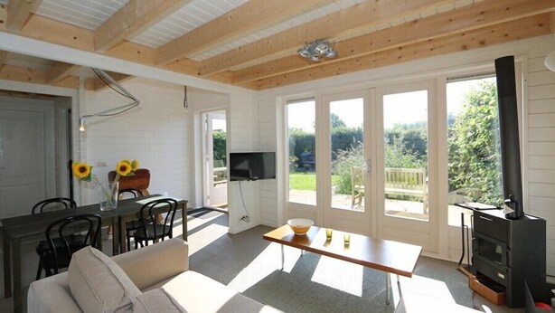 Amplia sala de estar con techo de madera, un sofá, una mesa de comedor y un televisor.