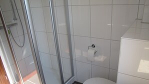 A modern bathroom with a glass-enclosed shower, a toilet, and a white cabinet.