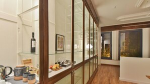 A modern kitchen with wooden cabinets, a glass backsplash, and a dining area with a white table and chairs. - República 157 (Porto)
