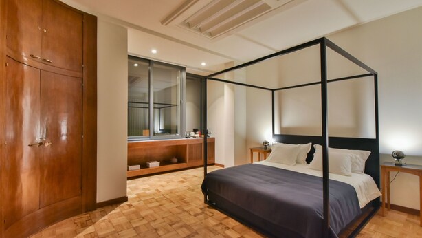 A bedroom with a four-poster bed, wooden wardrobe, and a large mirror. - República 157 (Porto)
