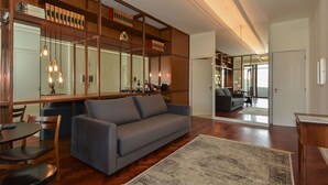 A spacious living room with a grey sofa, wooden shelving, and a large rug. - República 157 (Porto)