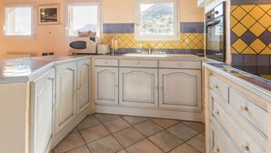 A kitchen with wooden cabinets, a tiled backsplash, and a window overlooking a mountainous landscape.