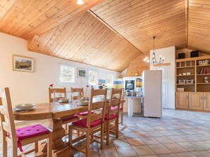 A cozy kitchen with wooden ceiling and walls, a dining table with chairs, and a refrigerator. - Spacious apartment in Briançon with private garage (Briançon)