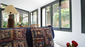 A room with a blue sofa, two plaid pillows, a lamp, and a vase with red flowers.