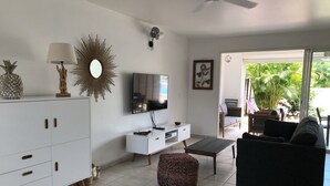 A modern living room with a flat-screen TV, white cabinetry, a coffee table, a black sofa, and a patterned ottoman. - T4 Duplex of 106 m² ideally located in the center of St Francois (Saint-François)