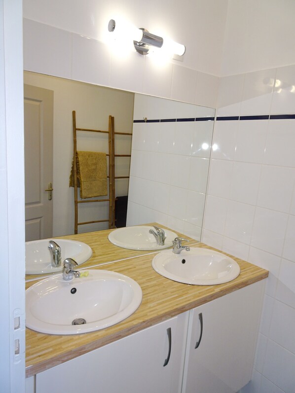 A bathroom with two sinks, a mirror, and a towel rack.