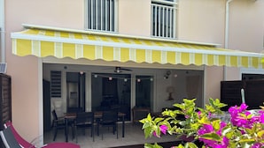 A covered patio with outdoor furniture, a dining area, and a view into the house. - T4 Duplex of 106 m² ideally located in the center of St Francois (Saint-François)