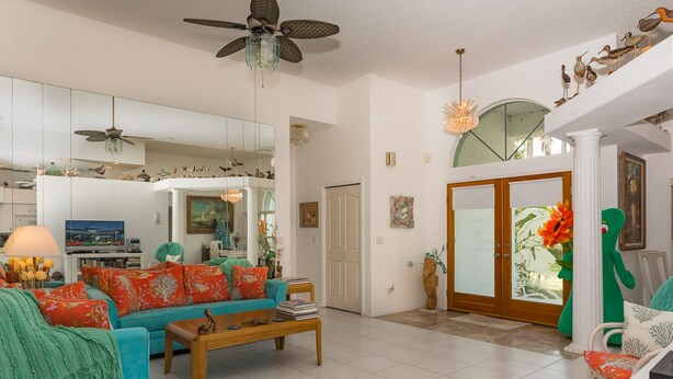 A spacious living room with a teal sofa, a wooden coffee table, and a ceiling fan. - Pet Friendly Coastal Retreat | Canal Access | Beach Nearby (New Smyrna Beach)