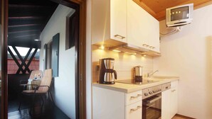 Eine moderne Küche mit weißen Schränken, einer Kaffeemaschine und einem Backofen. An der Wand über der Arbeitsfläche ist ein Fernseher angebracht.