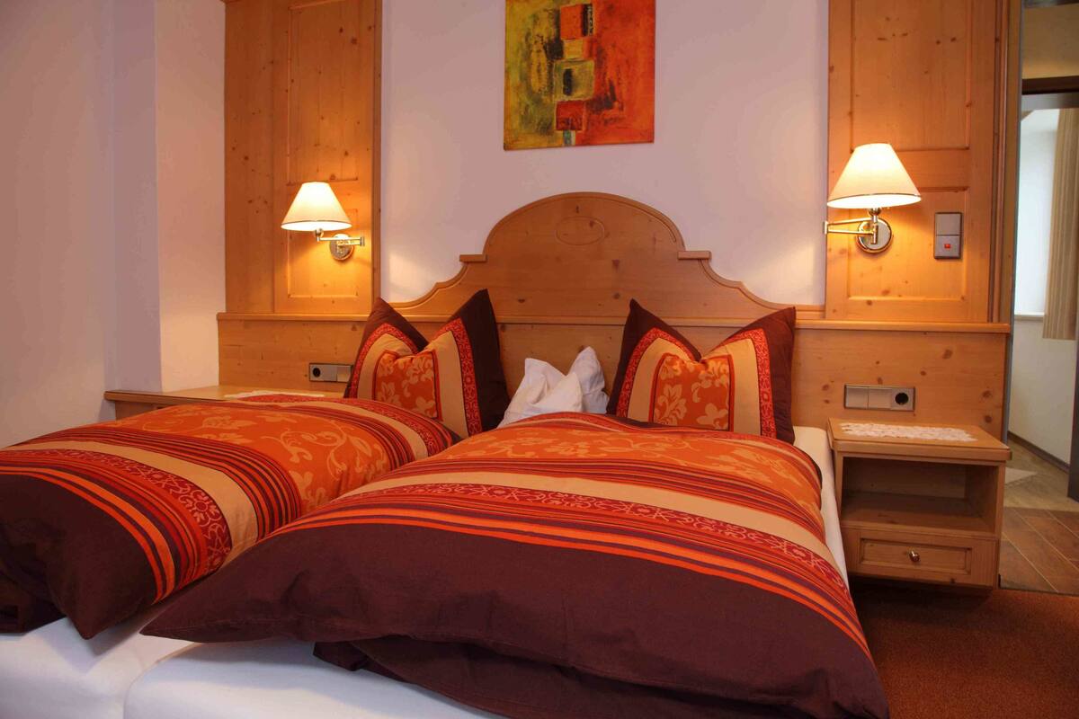 Un lit double avec deux oreillers, une tête de lit en bois et deux tables de chevet avec des lampes.