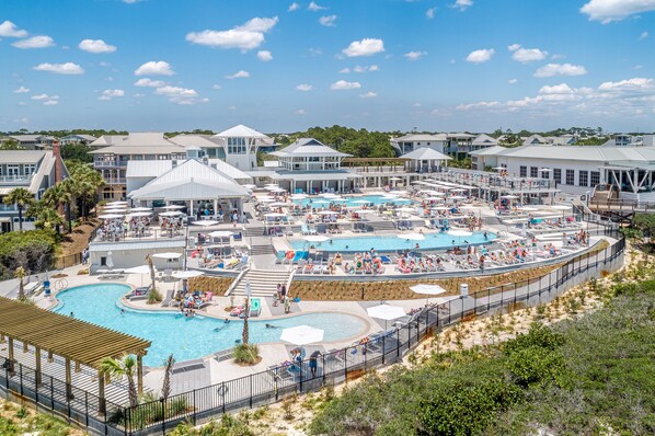 A large outdoor pool area with multiple swimming pools, sun loungers, and umbrellas.