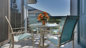 Eine Terrasse mit einem runden Tisch, vier Stühlen und einem Blumentopf.