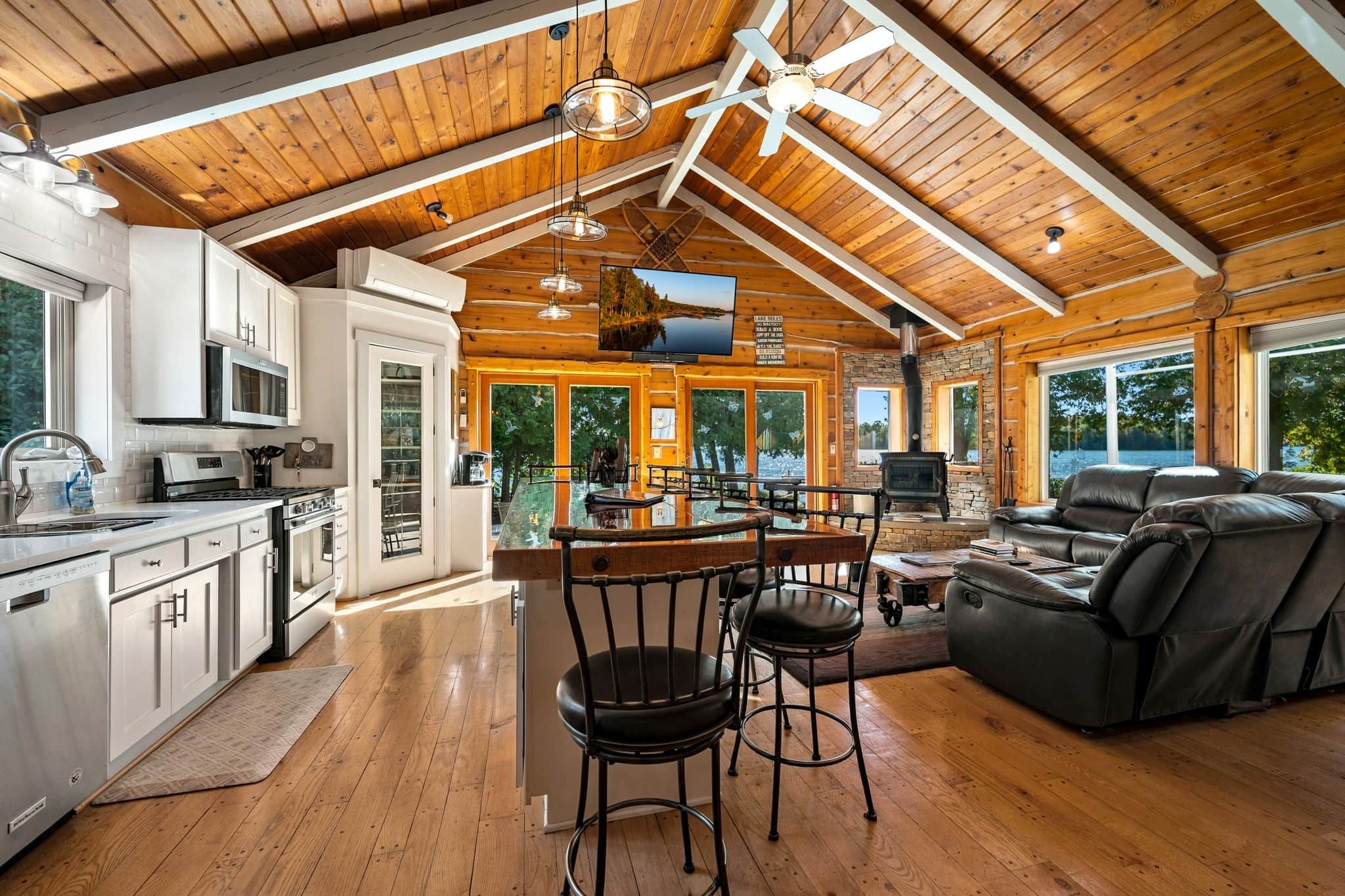 A spacious kitchen with modern appliances, a dining area with a bar stool, and a cozy seating area with a fireplace.