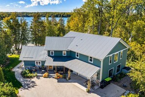 Une maison à deux étages dotée d’un patio couvert et offrant une vue sur un lac.