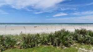 Ein Strand mit blauem Himmel, Wellen und Menschen in der Ferne.